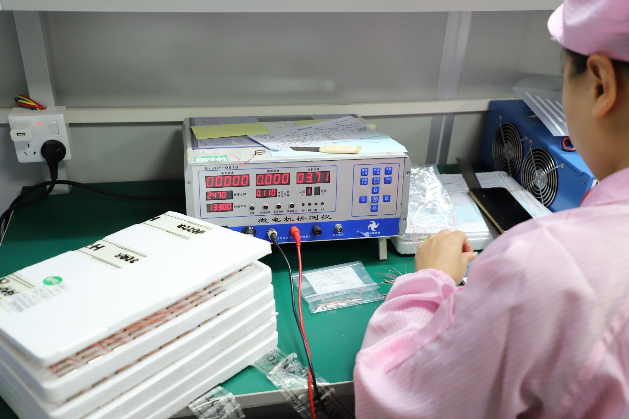 QC inspector testing incoming micro motors for speed and current on a motor tester
