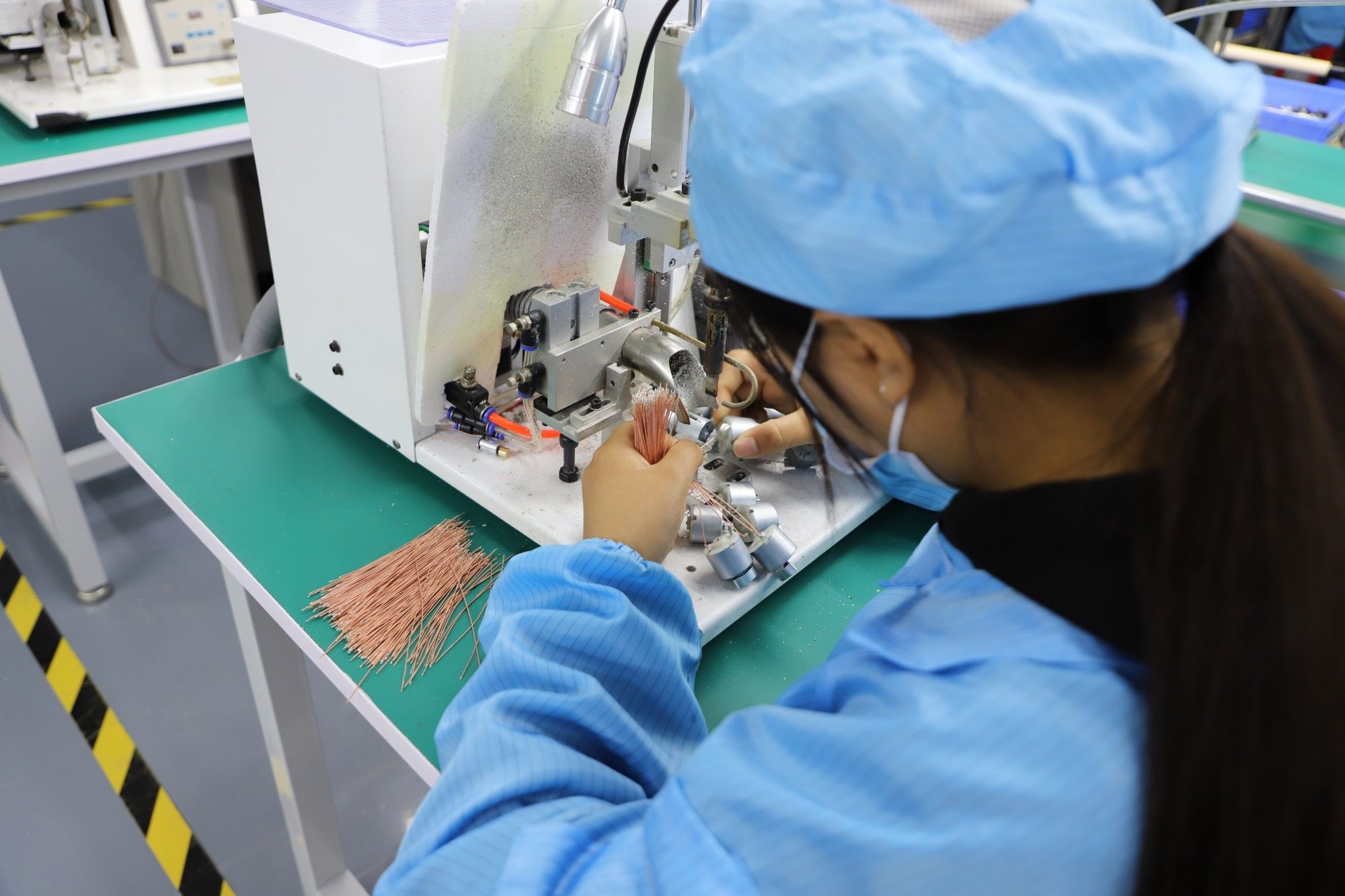 Operator soldering motor leads on a semi-automatic soldering machine before silicone encapsulation
