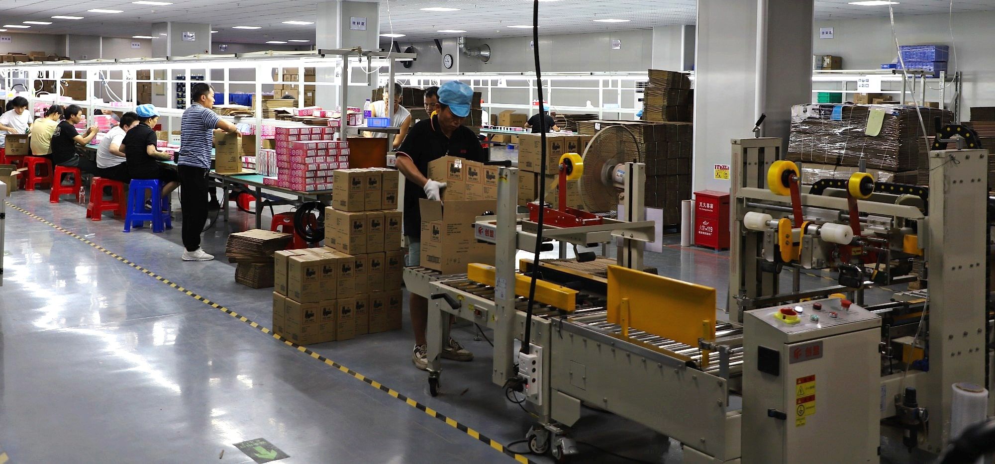 Packing line with retail boxing tables and an automatic carton sealer